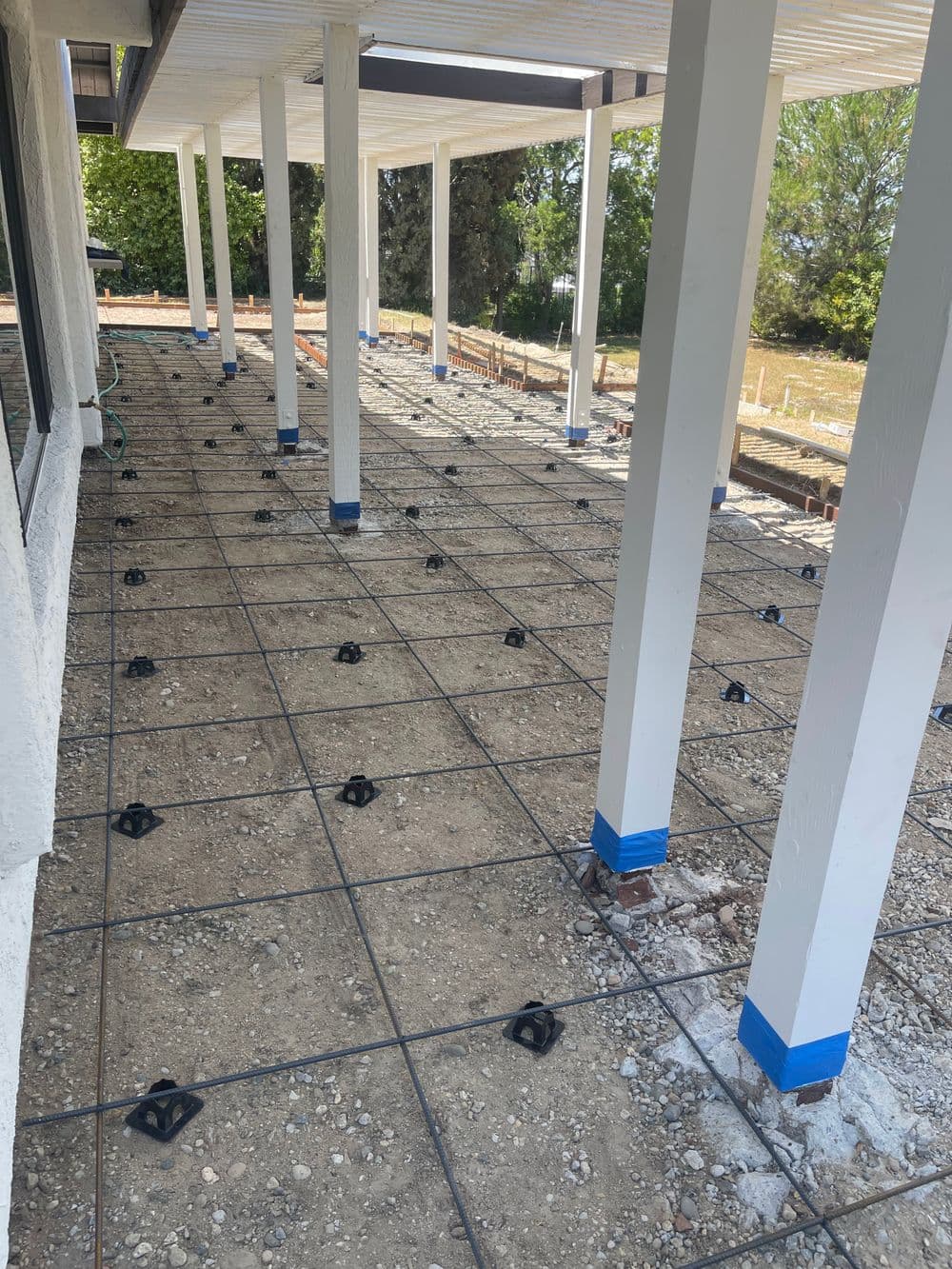 Construction site featuring leveled foundation with steel reinforcement bars and support columns.