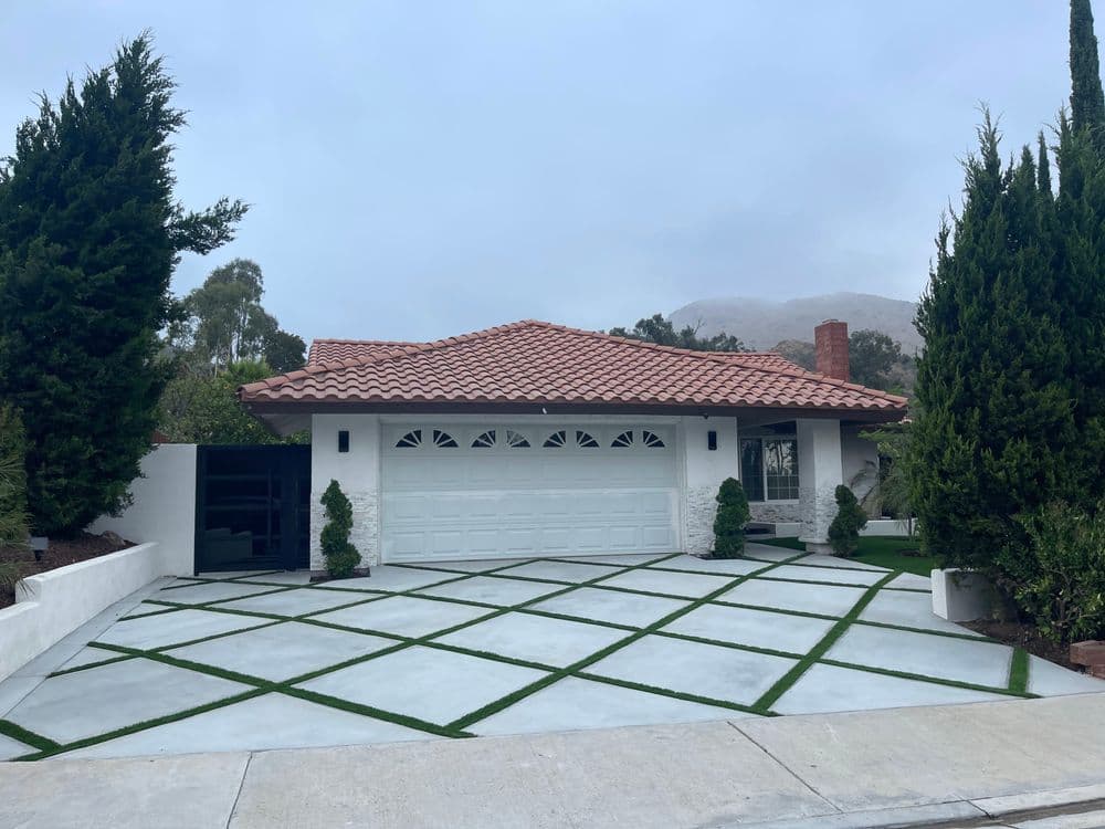Modern house with a red tile roof, driveway, and landscaped front yard.